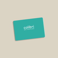 Karte mit der Aufschrift "colibri SKINCARE" in Weiß auf einem türkisfarbenen Hintergrund, schräg auf beigefarbenem Untergrund.
